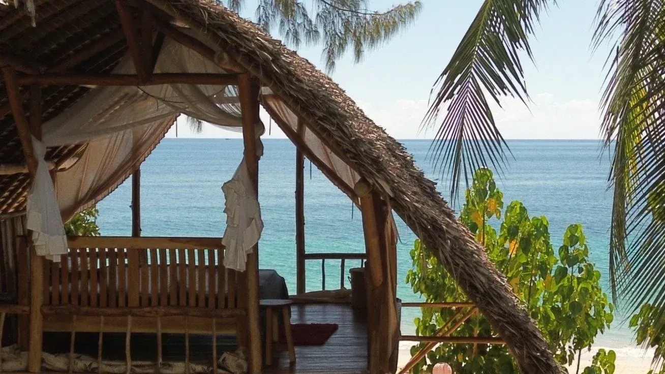 Blick aus dem Beach Bed durch Palmen auf den Indischen Ozean