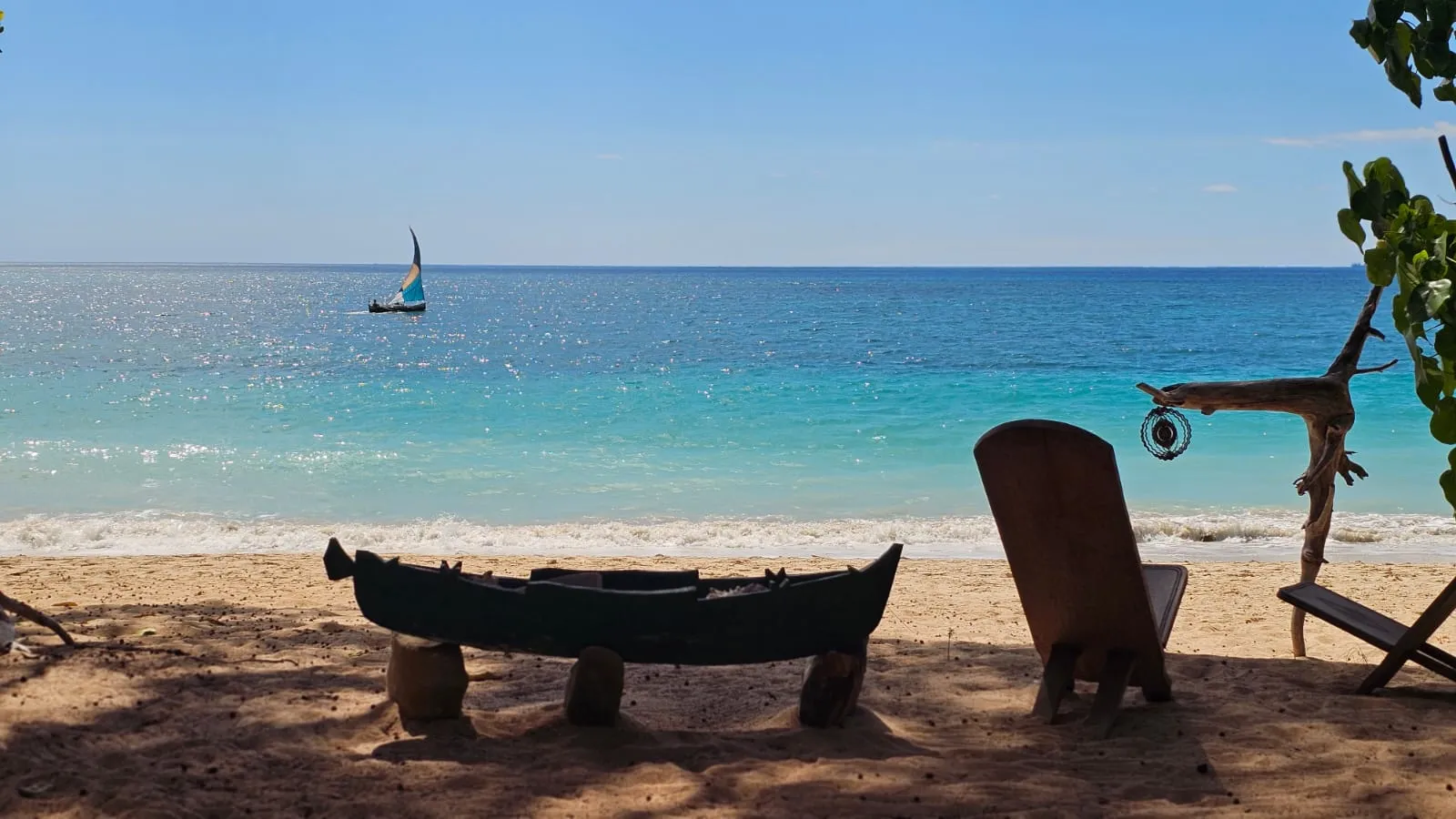 Traditionelle Piroge und Segelboot vor dem Strand von Ampohana