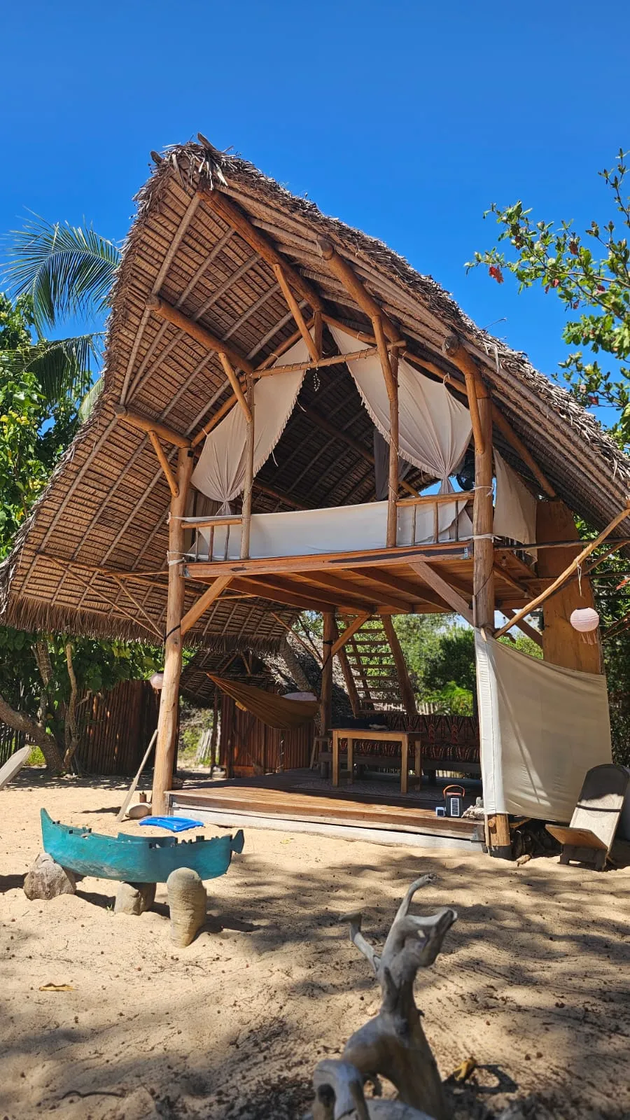 Das zweistöckige Spirit Beach Bed mit Palmdach und weißem Himmelbett am Strand von Ampohana