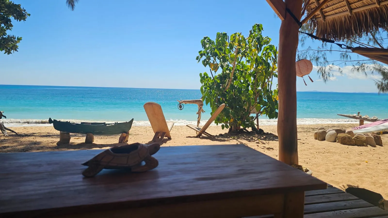 Holzliegen mit Blick auf das türkisblaue Meer am Strand von Ampohana